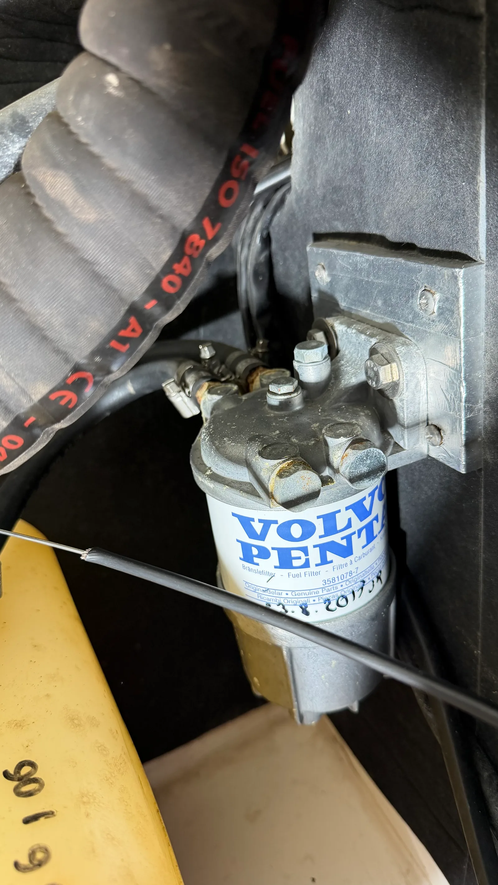 Original installation before refit: pre-filter block bulkhead-mounted with a genuine Volvo Penta spin-on filter dated 2019, black marine diesel hose with ISO 7840 A1 marking clearly visible