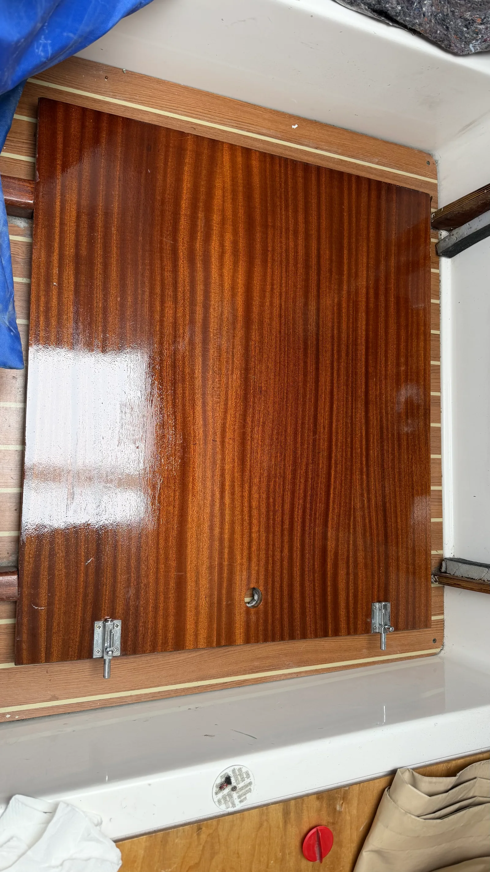 Engine-bay wood panel with fresh Wood Line varnish, glossy wet film revealing the mahogany grain