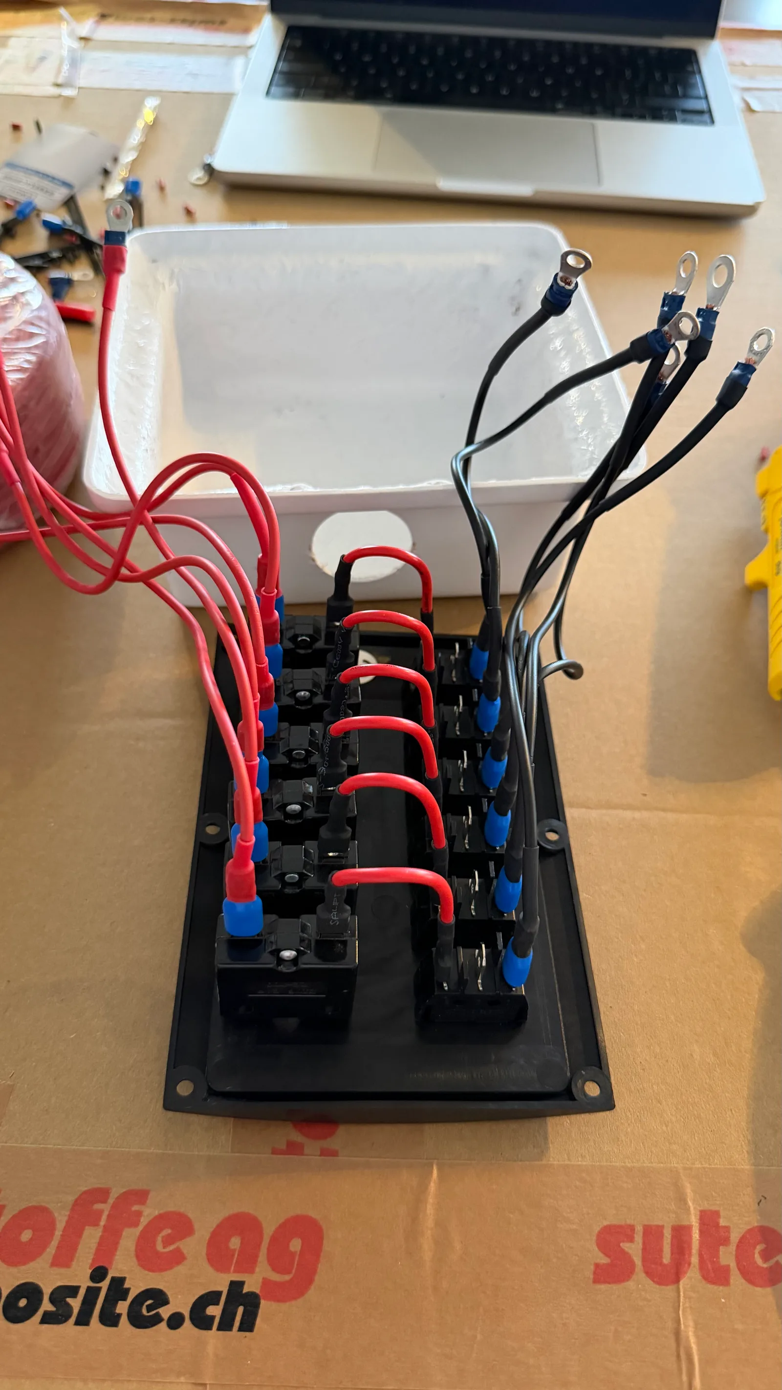 Tableau neuf pré-câblé sur établi, à l'envers pour accéder aux terminaisons : alimentation positive dédiée en 1,5 mm² sur chaque disjoncteur, aucun pont fusible à fusible — la même image illustre pourquoi le tableau sorti d'usine ne convient pas et ce qui a été mis en place à la place